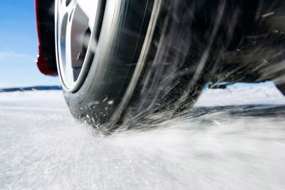 Närbild på ett däck, en bil som kör på is.